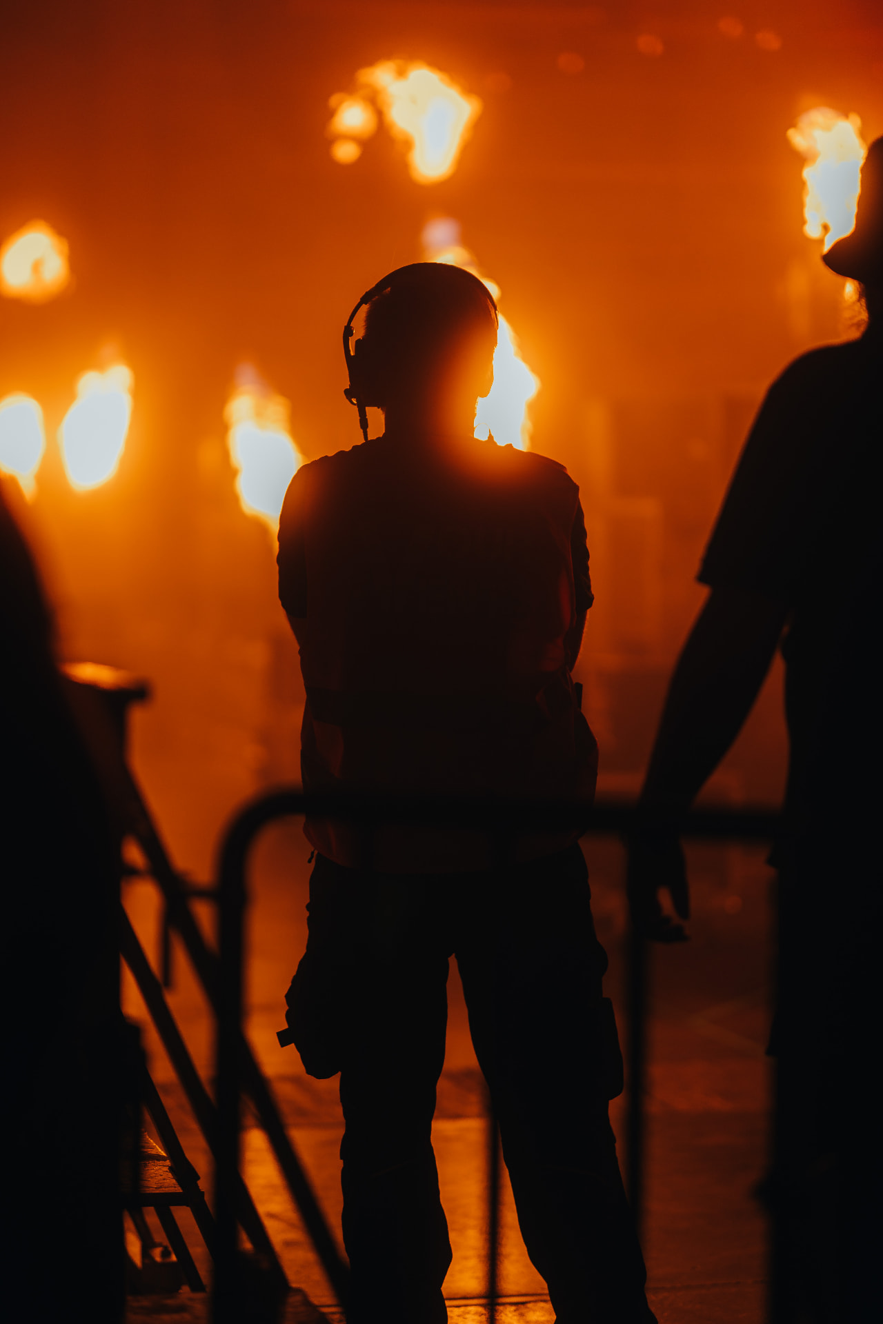 Crew member silhouetted against orange flame bursts — Bassment Festival, photographed by Paul Rumplmaier
