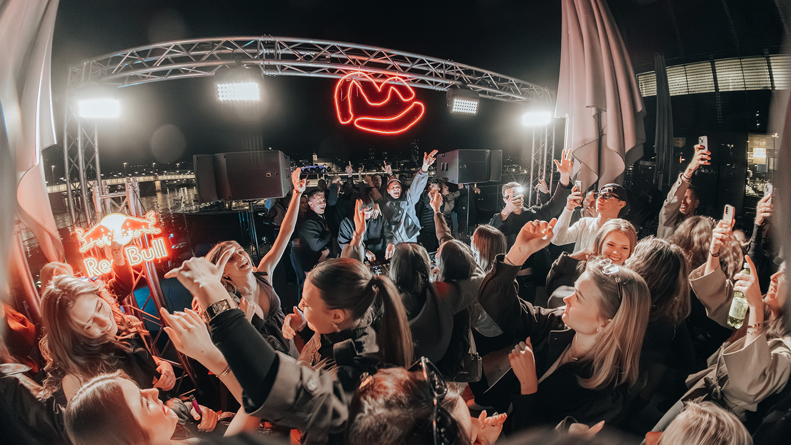 Crowd dancing under the neon sign at the riverside stage — Bisou.at, photographed by Paul Rumplmaier
