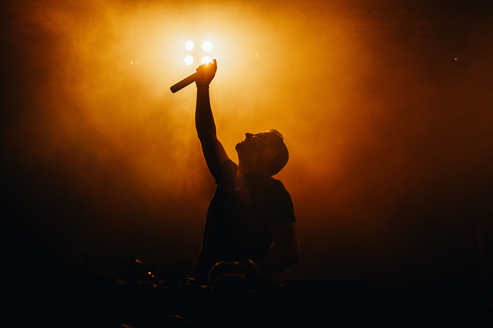 Singer raising the microphone into orange backlight and haze — Best of, photographed by Paul Rumplmaier