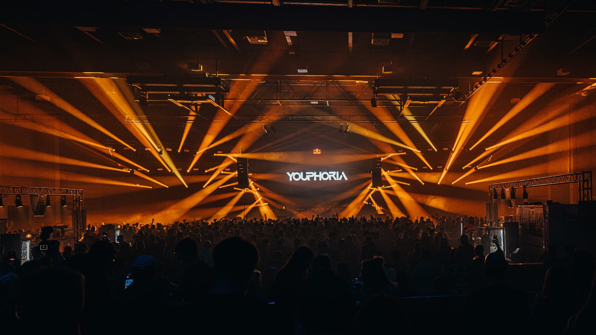 Youphoria stage bathed in orange beams above a packed crowd — Bassment Festival, photographed by Paul Rumplmaier