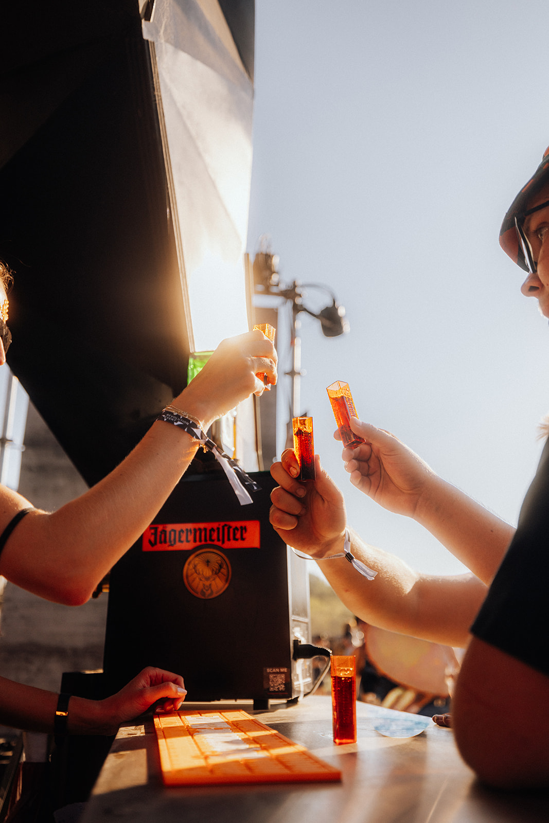 Guests toasting with shots at the bar in the evening sun — Shutdown Festival, photographed by Paul Rumplmaier