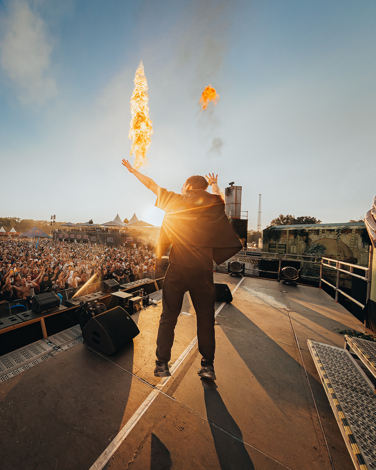 Artist facing the crowd with arms raised as flame jets fire — Shutdown Festival, photographed by Paul Rumplmaier