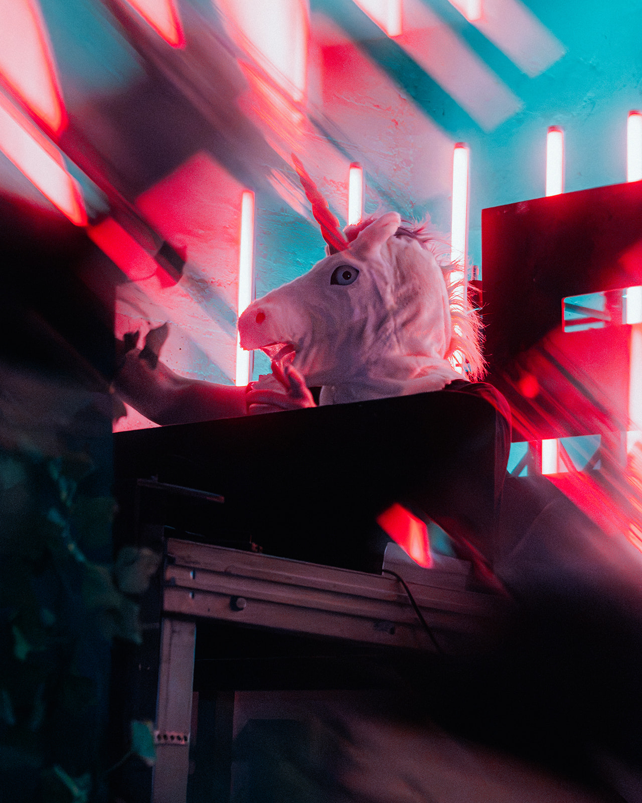 Performer in a unicorn mask under red and cyan neon tubes — Shutdown Festival, photographed by Paul Rumplmaier