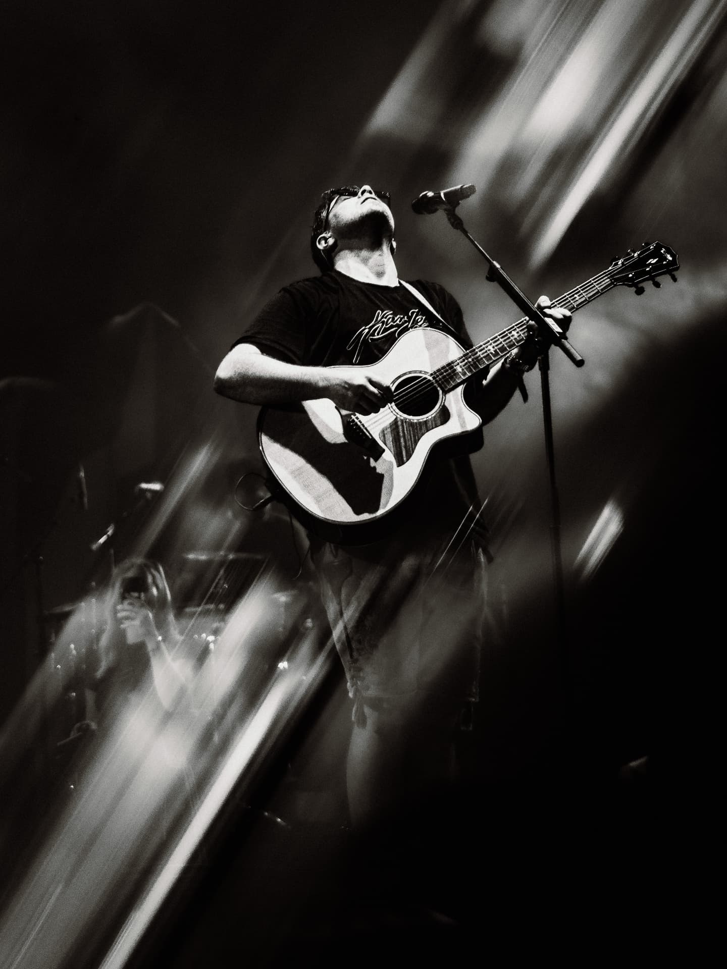 Black and white frame of a singer with acoustic guitar on stage — Woodstock der Blasmusik, photographed by Paul Rumplmaier