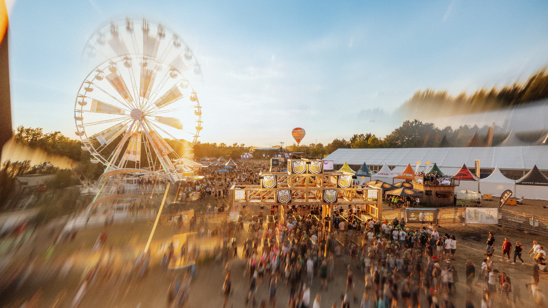 Festival grounds at golden hour with the ferris wheel above the crowd — Woodstock der Blasmusik, photographed by Paul Rumplmaier